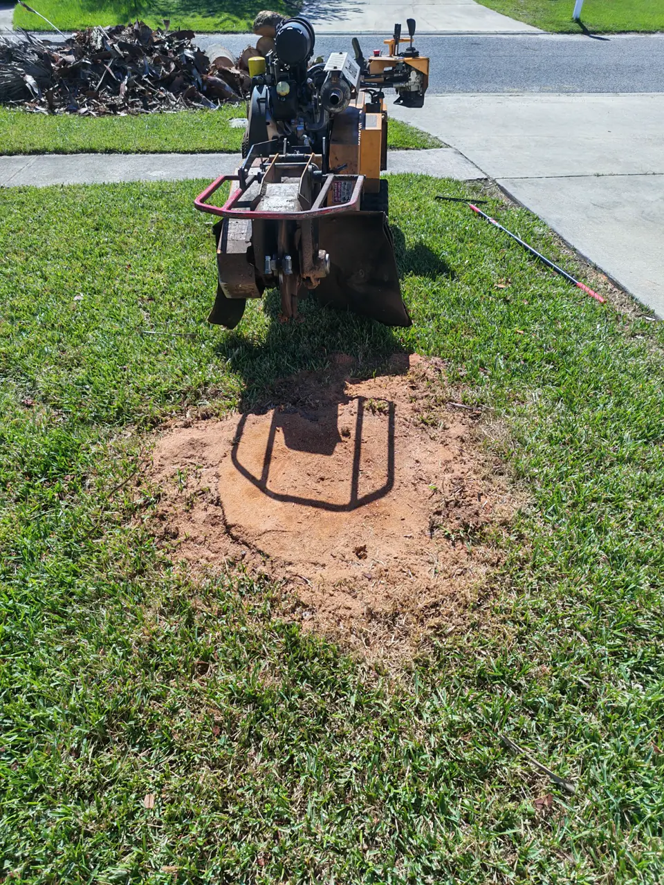 Stump grinder at the work area beside a driveway